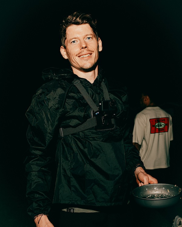 Crew member cooking a warm meal at camp during a backyard ultra
